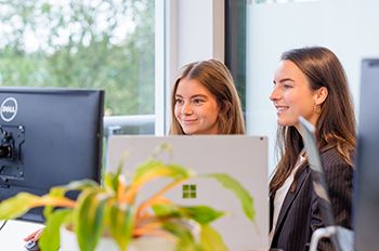 Twee collega’s bekijken samen een scherm en werken aan online klantreistraject